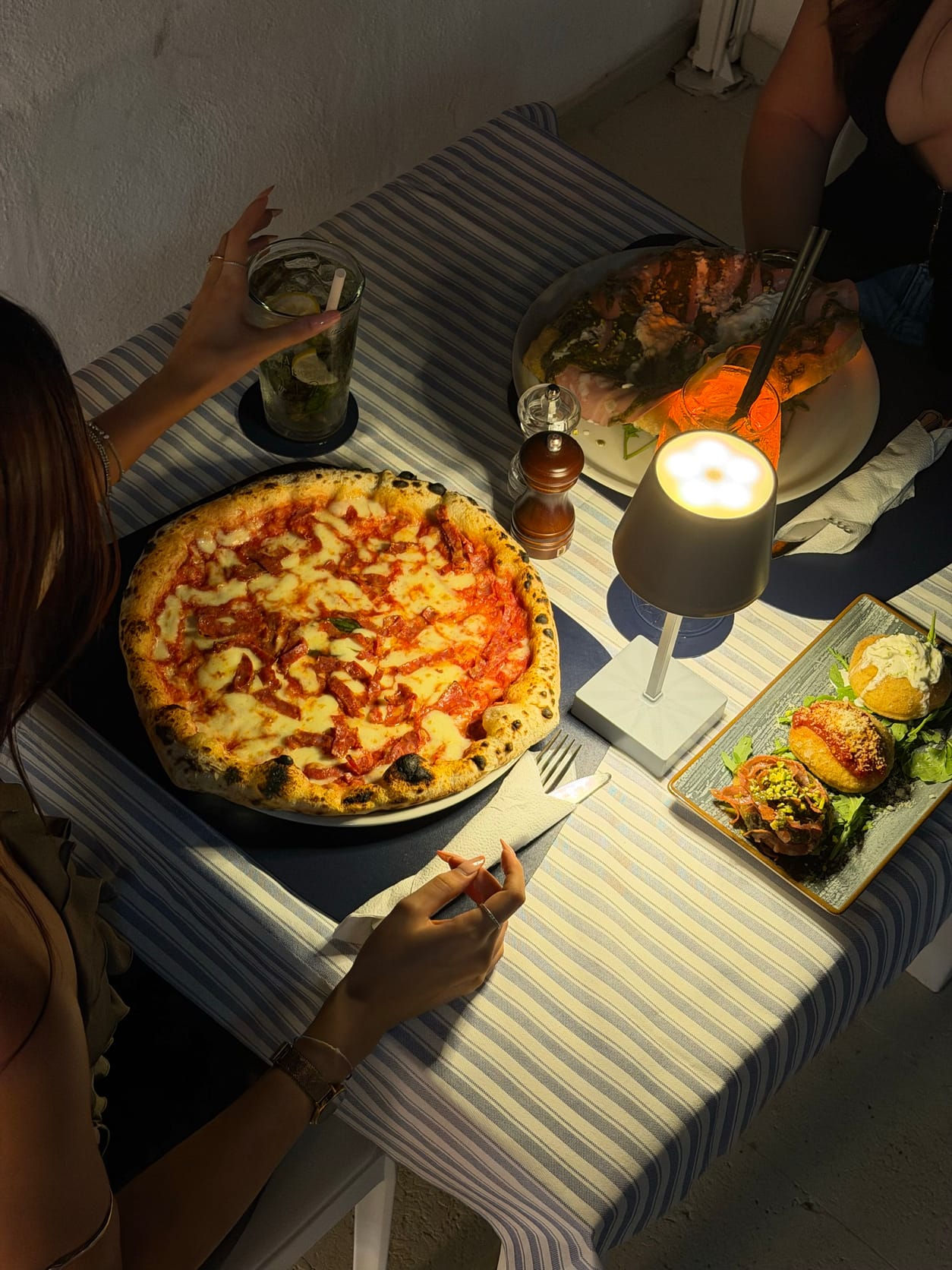 Tavolo la sera con pizza, fritti e cocktail sulla terrazza di Marina Due Golfi