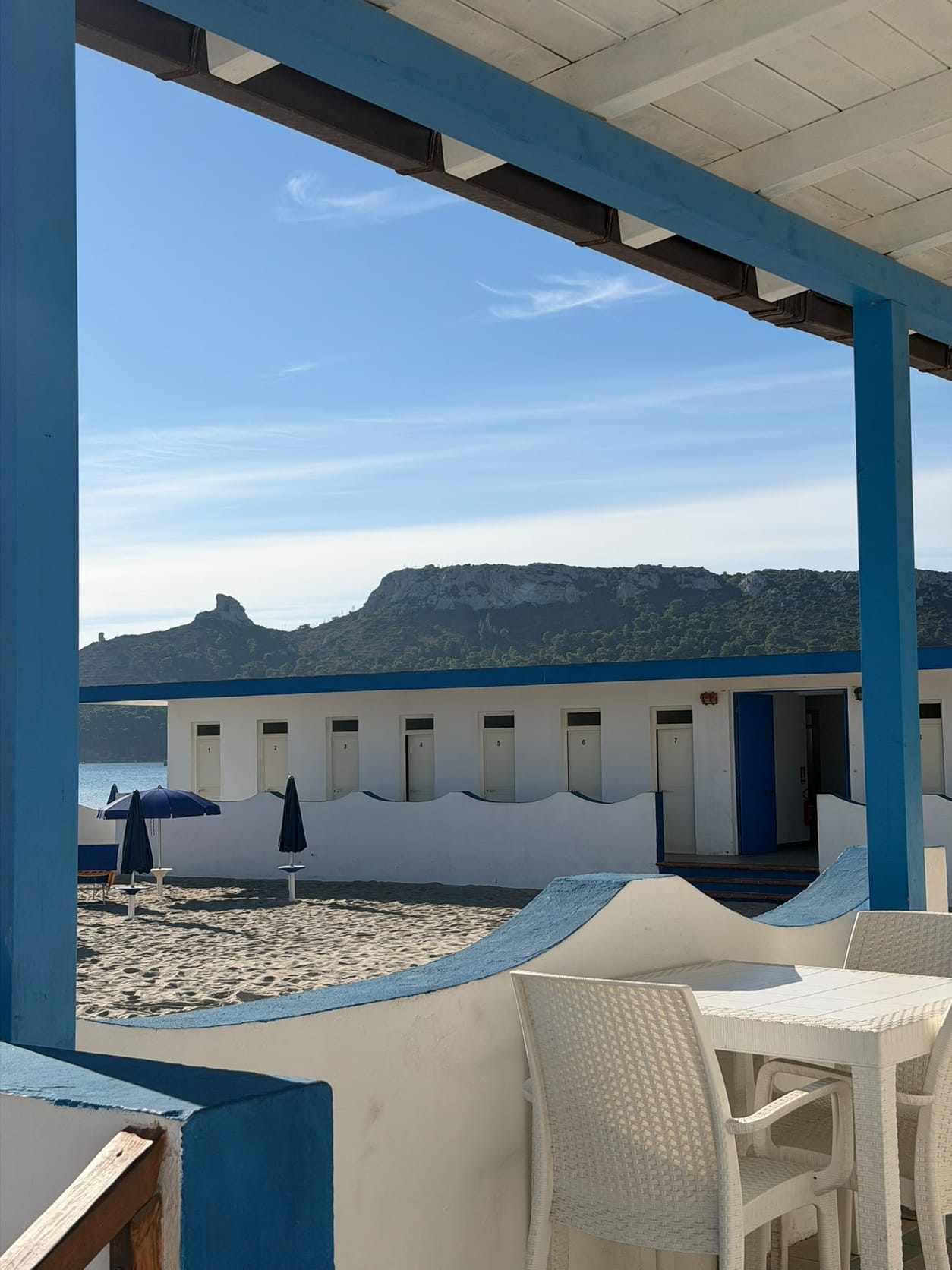 Veranda con colonne blu affacciata sulla spiaggia e sulla Sella del Diavolo